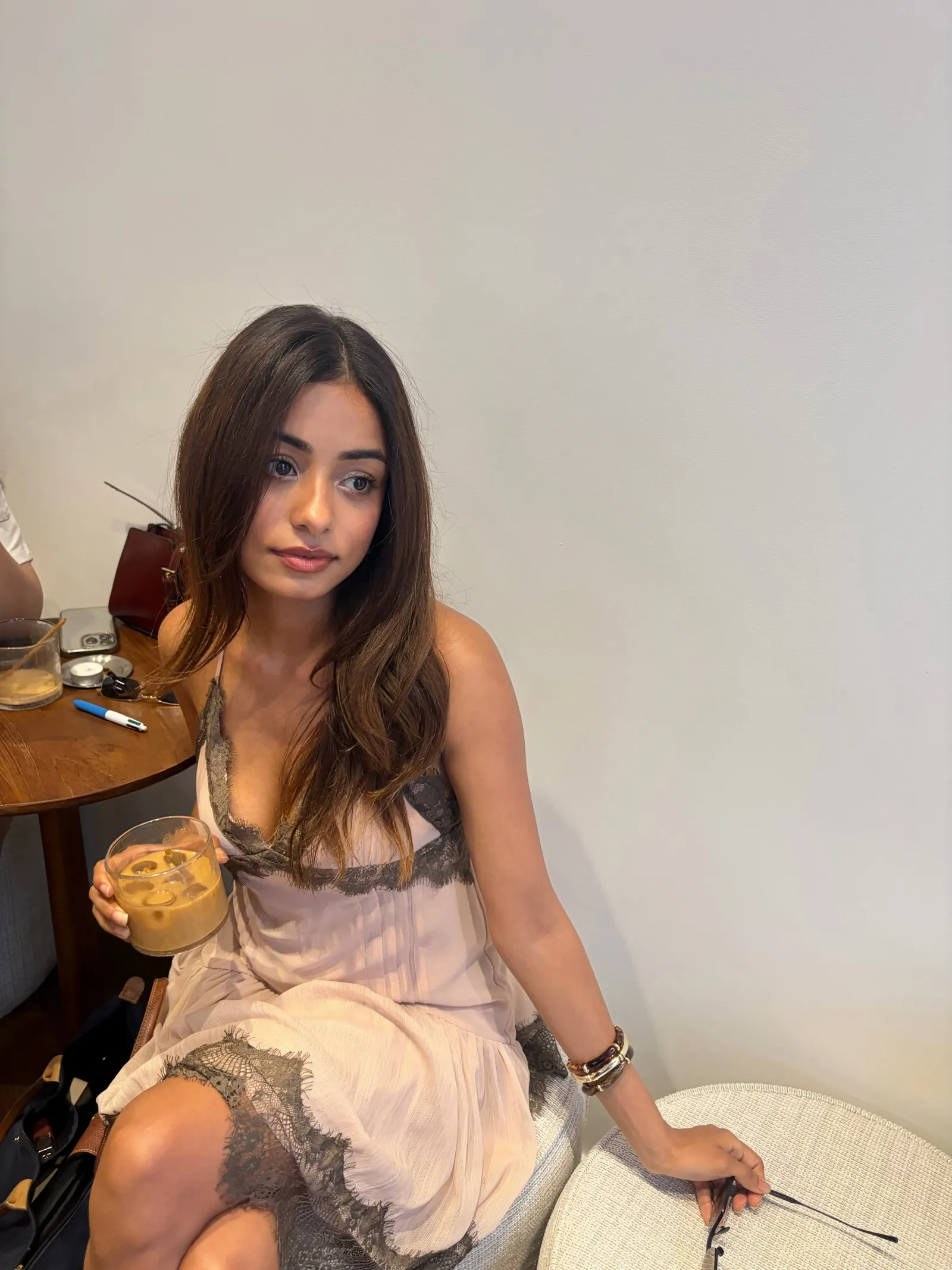 Sukhmani, founder of The Original Coffee Club, seated with an iced coffee.
